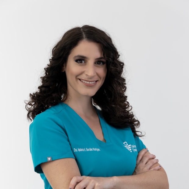 Dr. Nadia Rahmani, smiling in teal scrubs with her arms folded
