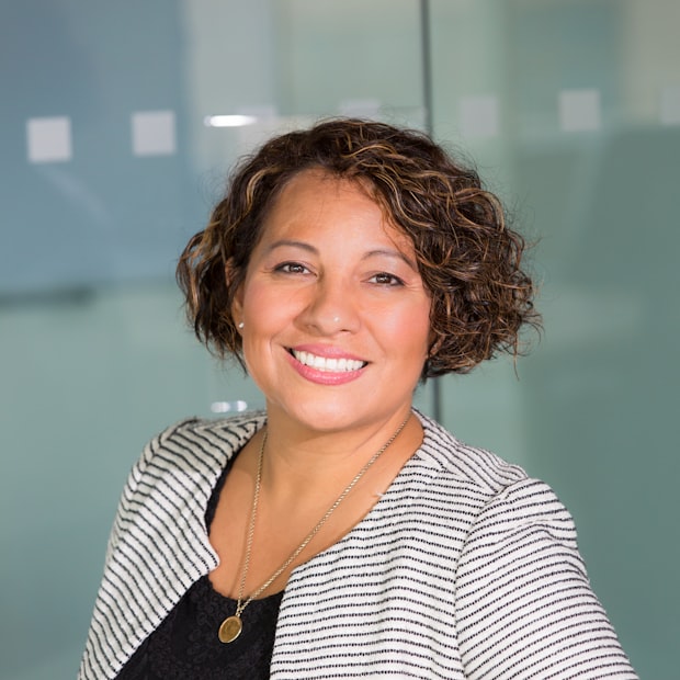 Priya Vela, lead hygienist, smiling in a striped jacket
